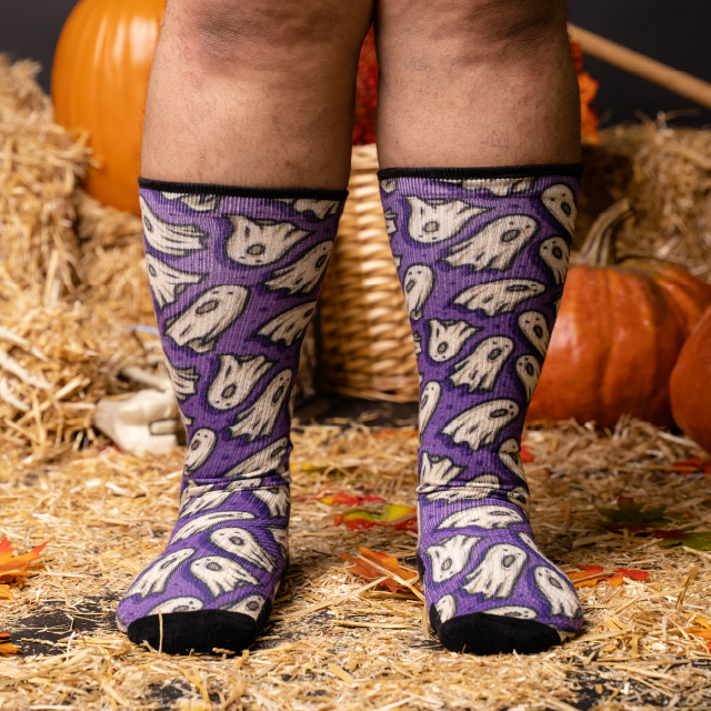 Two feet wearing compression socks with pumpkins and basket at the back