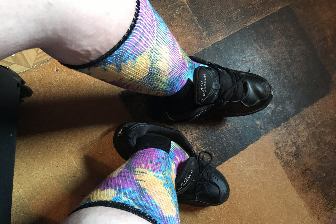 Legs of a lady wearing black boots and multicolor non-binding diabetic socks