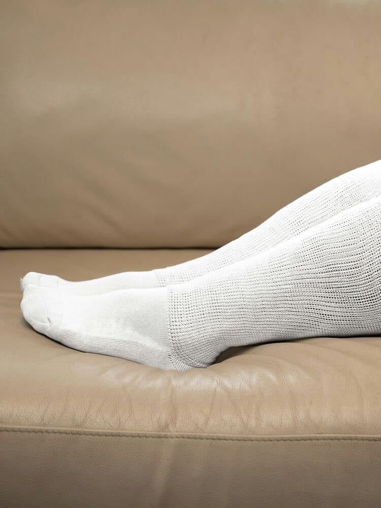 White EasyStretch™ socks worn with feet up on a sofa