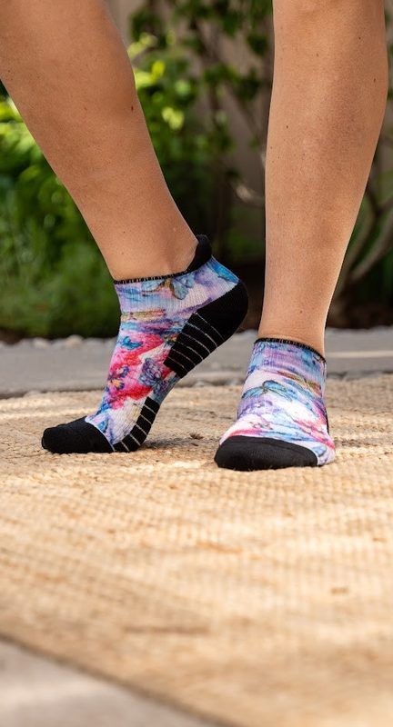 Standing in pink and purple floral ankle compression socks on a woven rug