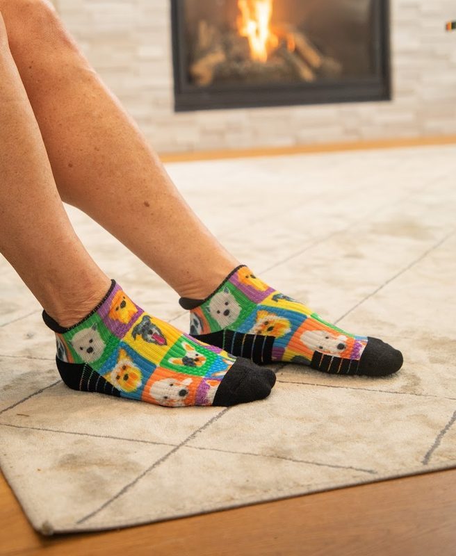 Legs stretched toward a fireplace in colourful pop-art ankle compression socks